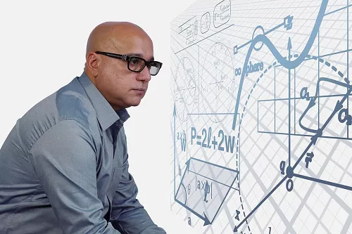 bespectacled mathematician in front of a white board with advanced formulas
